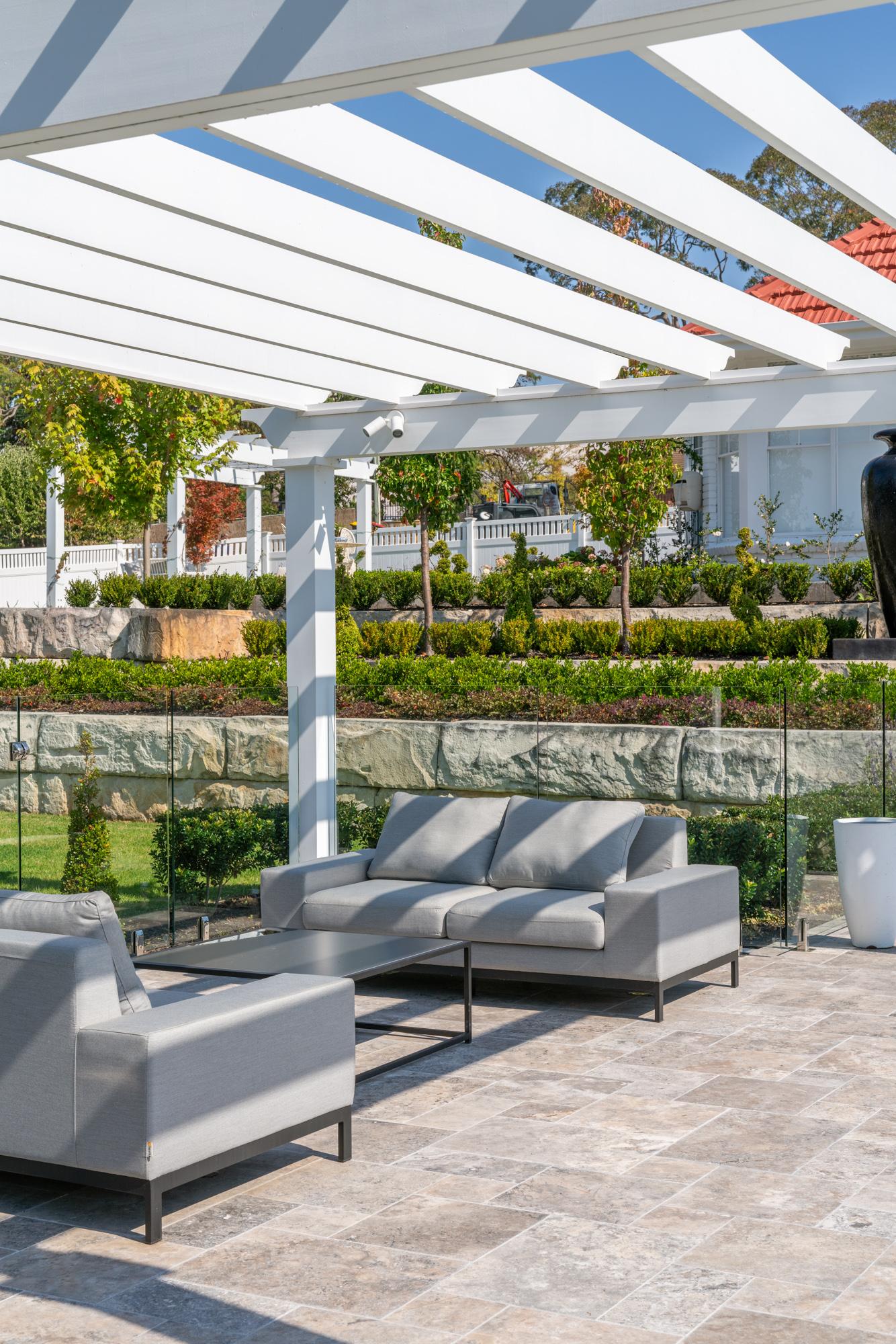 Pergola lounge overlooking a terraced garden and red-tiled roof beyond